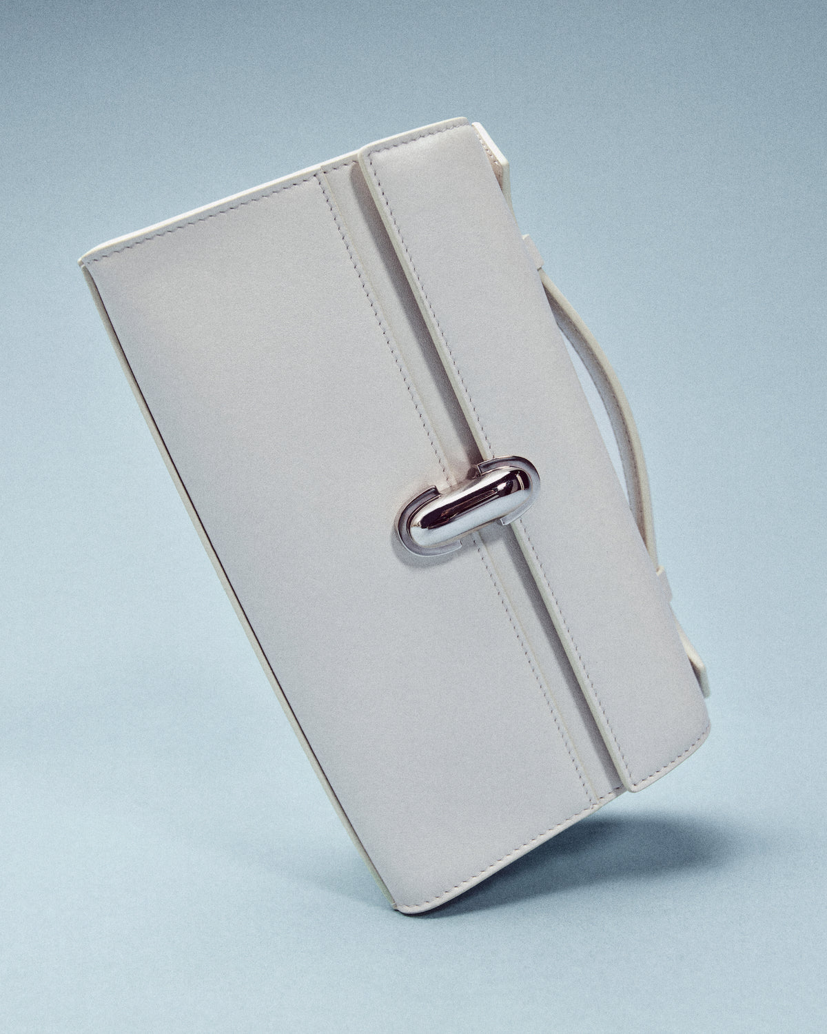 editorial image of an ivory bag with a silver clasp