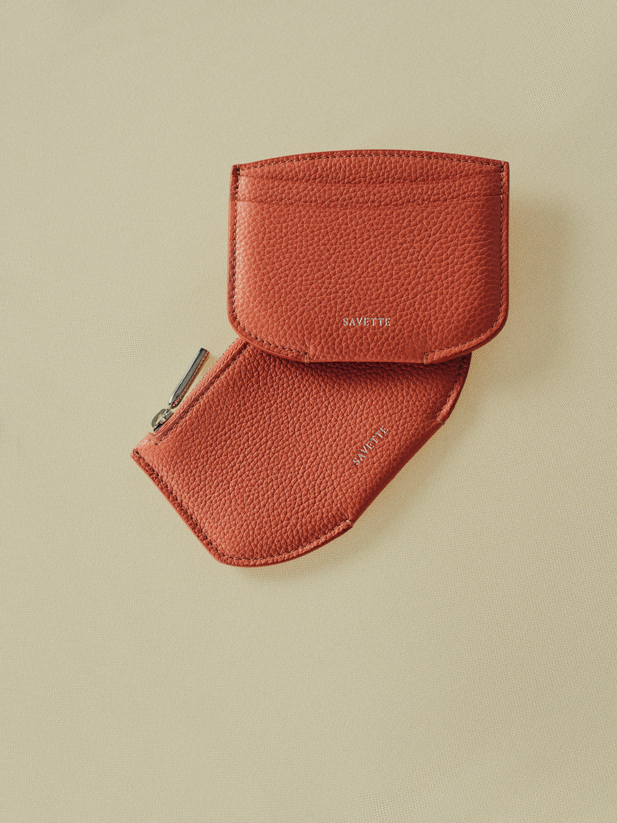 campaign aerial view of a maple brown chevre cardholder and zipper waller on a beige background