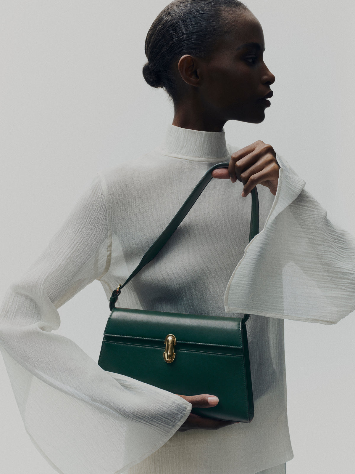 campaign on model image of pine green bag with gold clasp on a white background