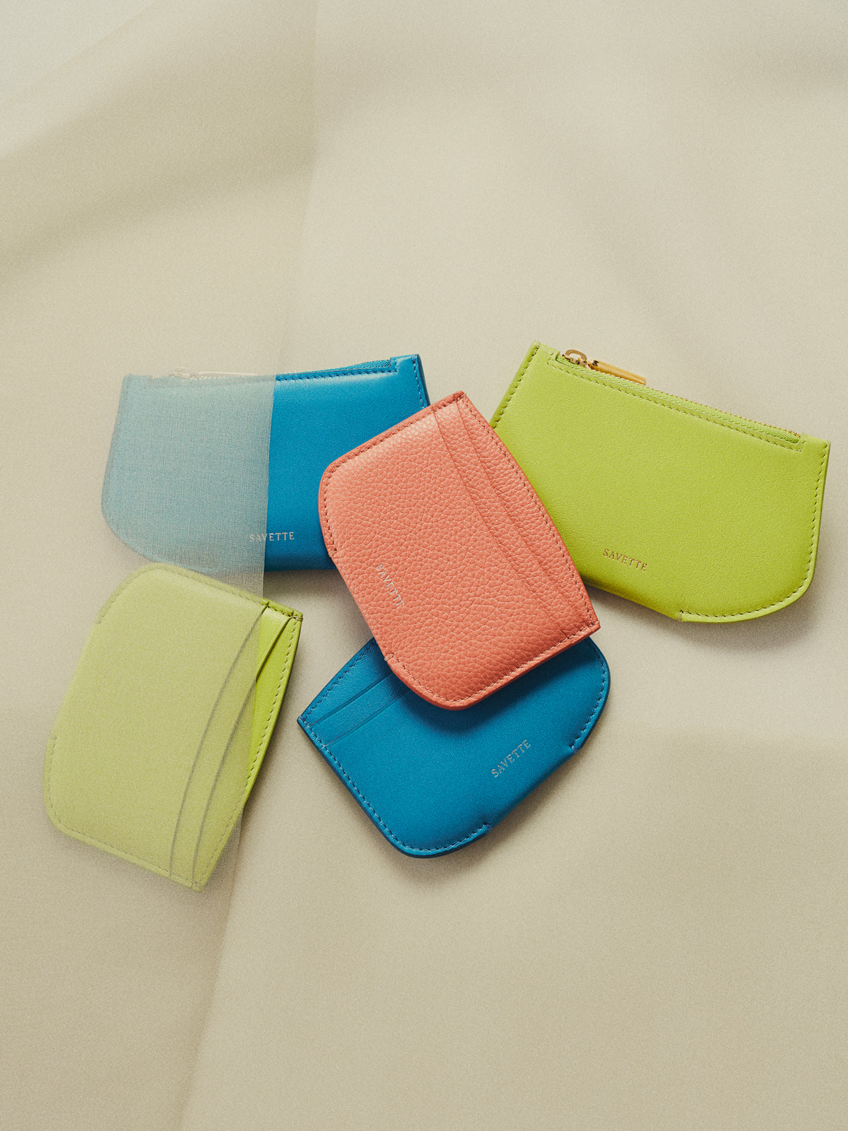 campaign aerial view of blue, pink, and lime green wallets on an off white background