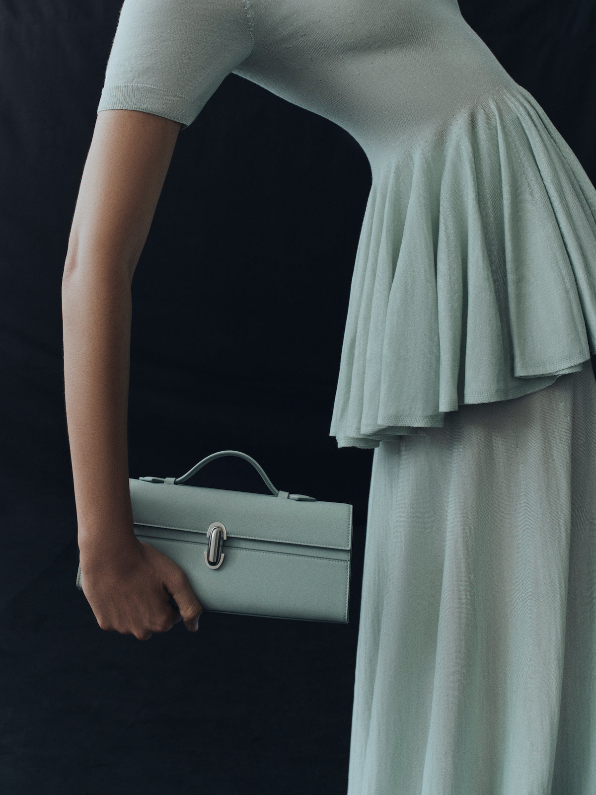 campaign on model image of mist green bag with silver clasp on a black background