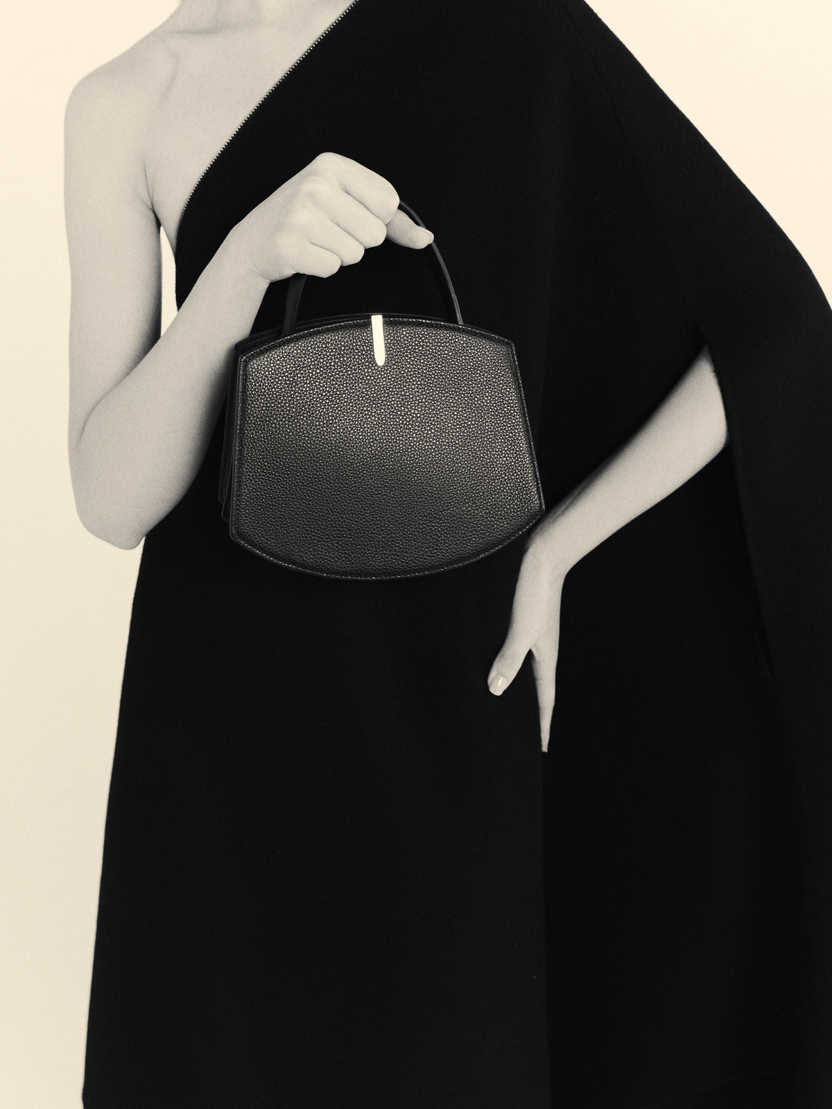 black and white on model image of a black bag with silver hardware on a white background