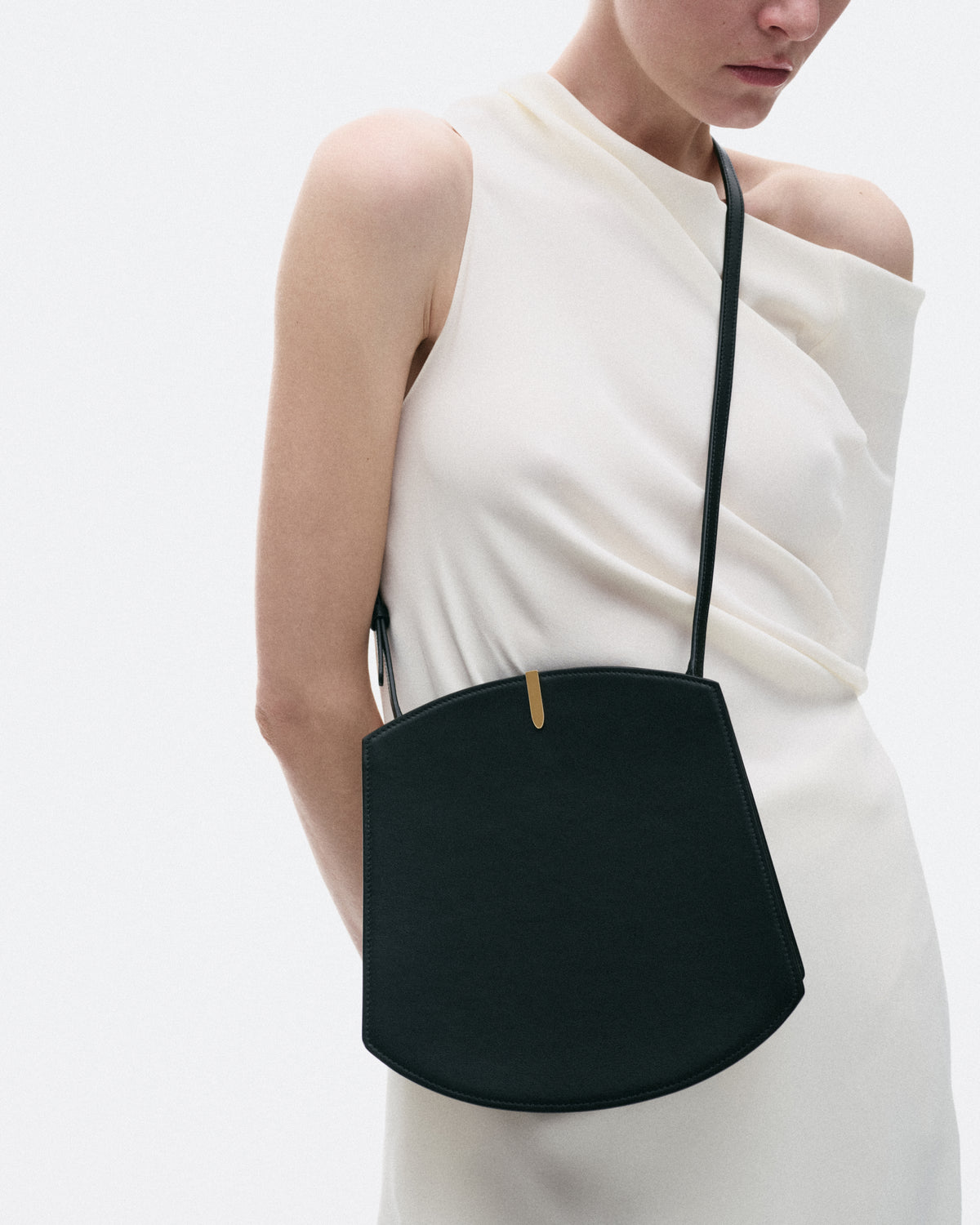 on model image of crossbody black bag with gold hardware on a white background