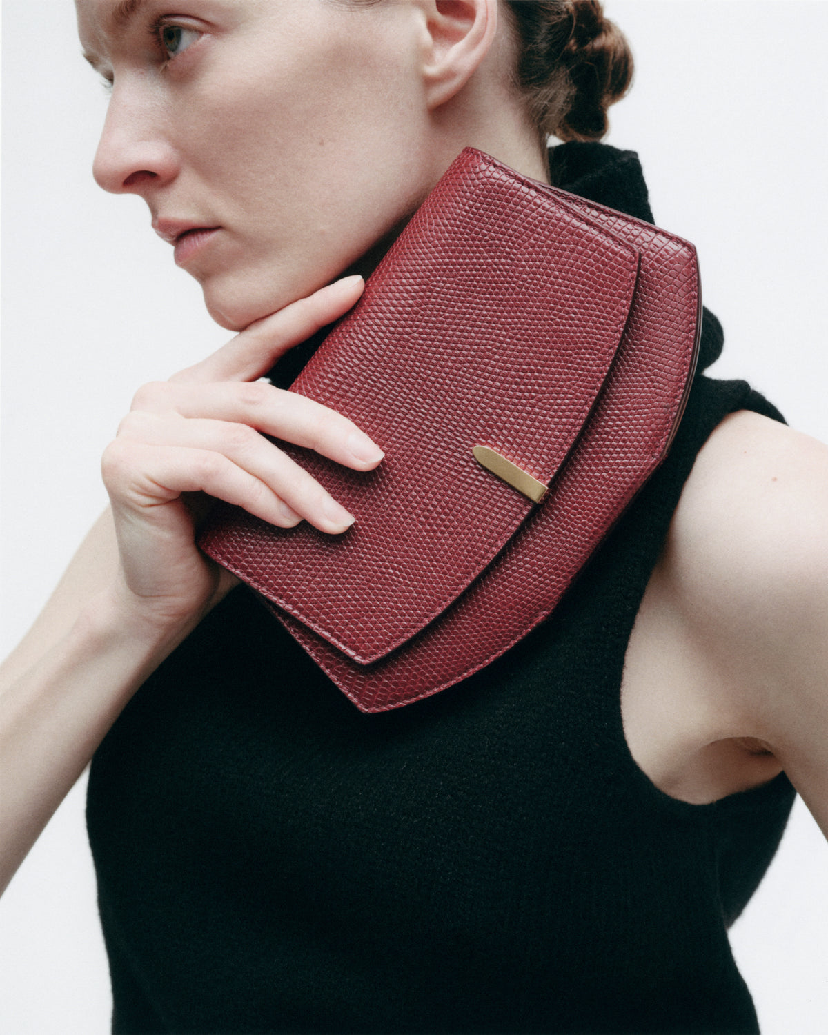 on model image of a wine red lizard clutch with gold hardware