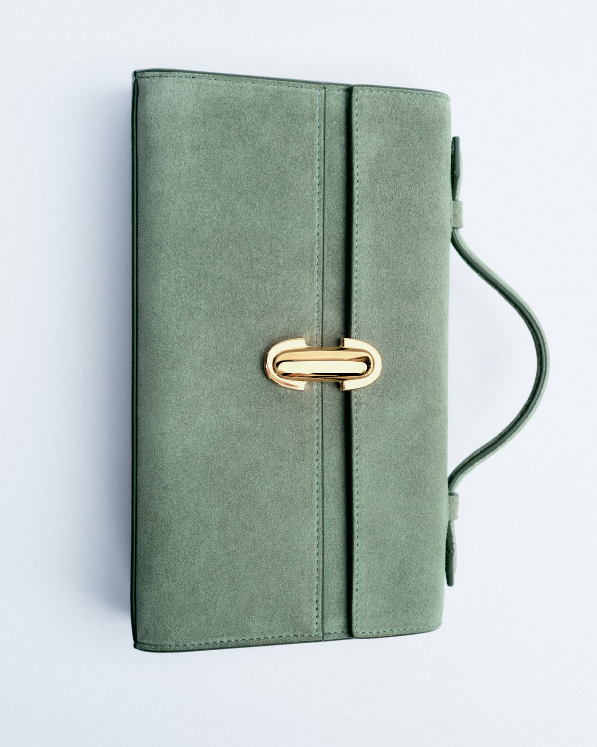 campaign aerial view of a cactus green suede bag with a gold clasp on a white background