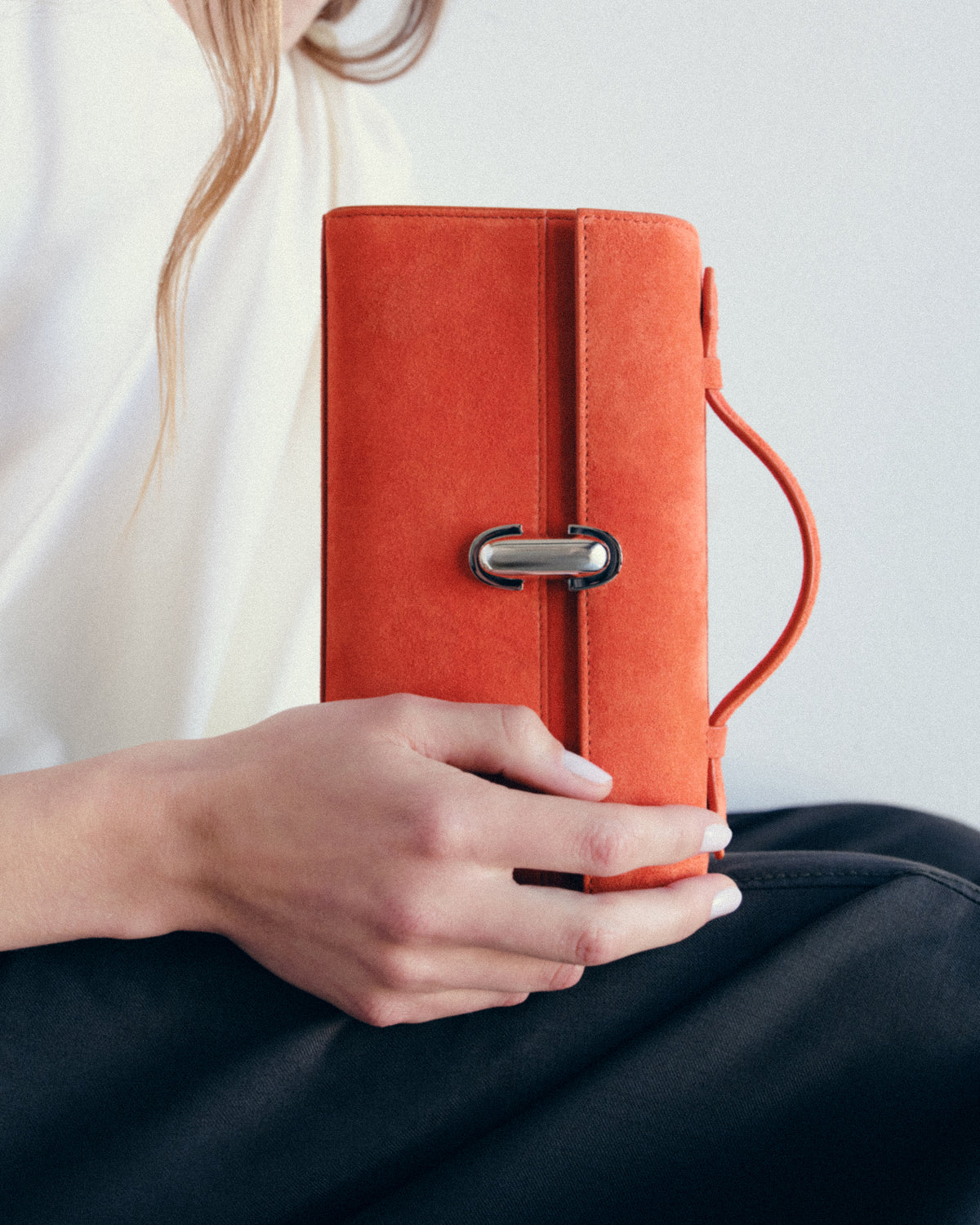 campaign image of tangerine orange suede bag with silver clasp on a white background