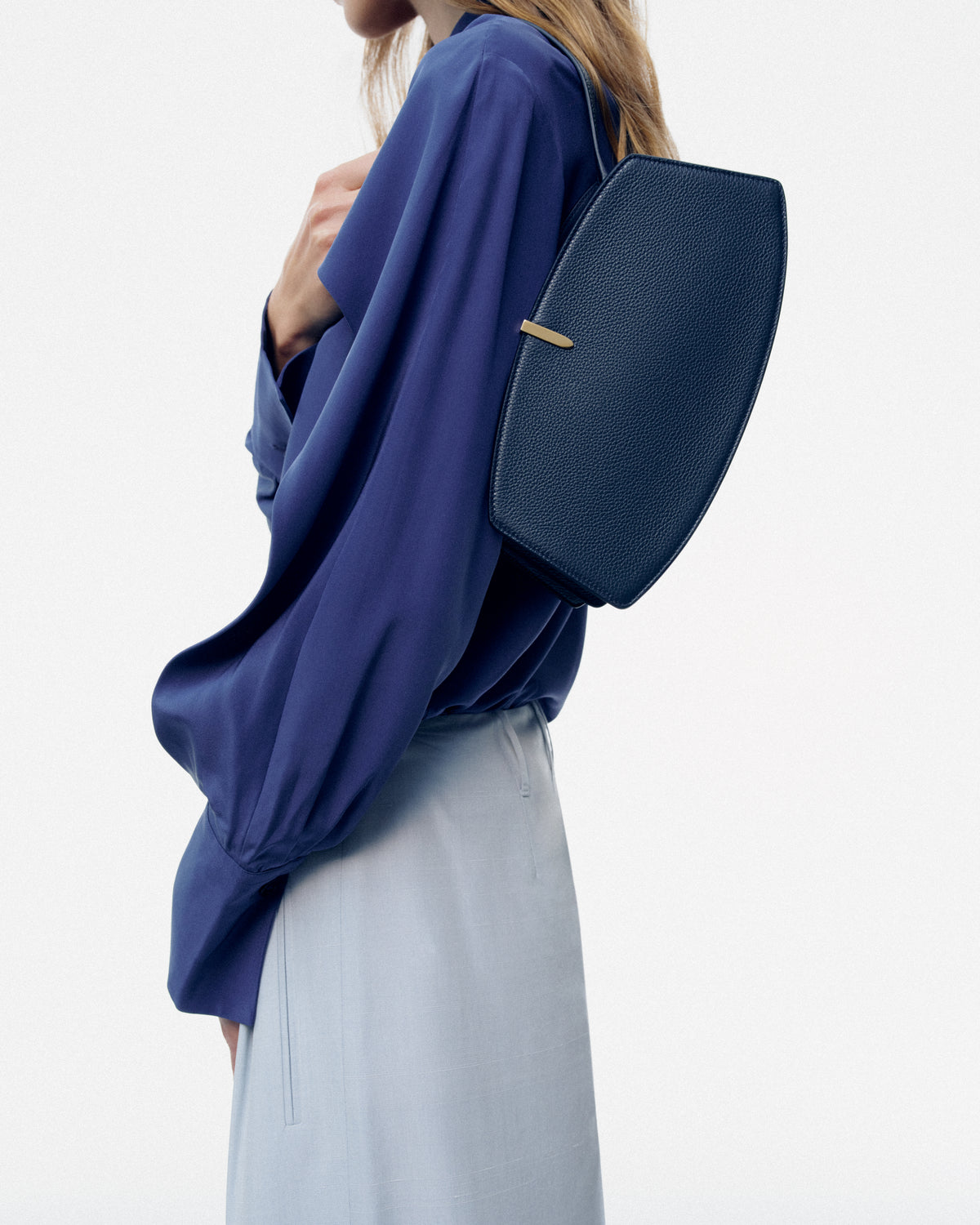 on model image of navy blue bag with gold hardware on a white background