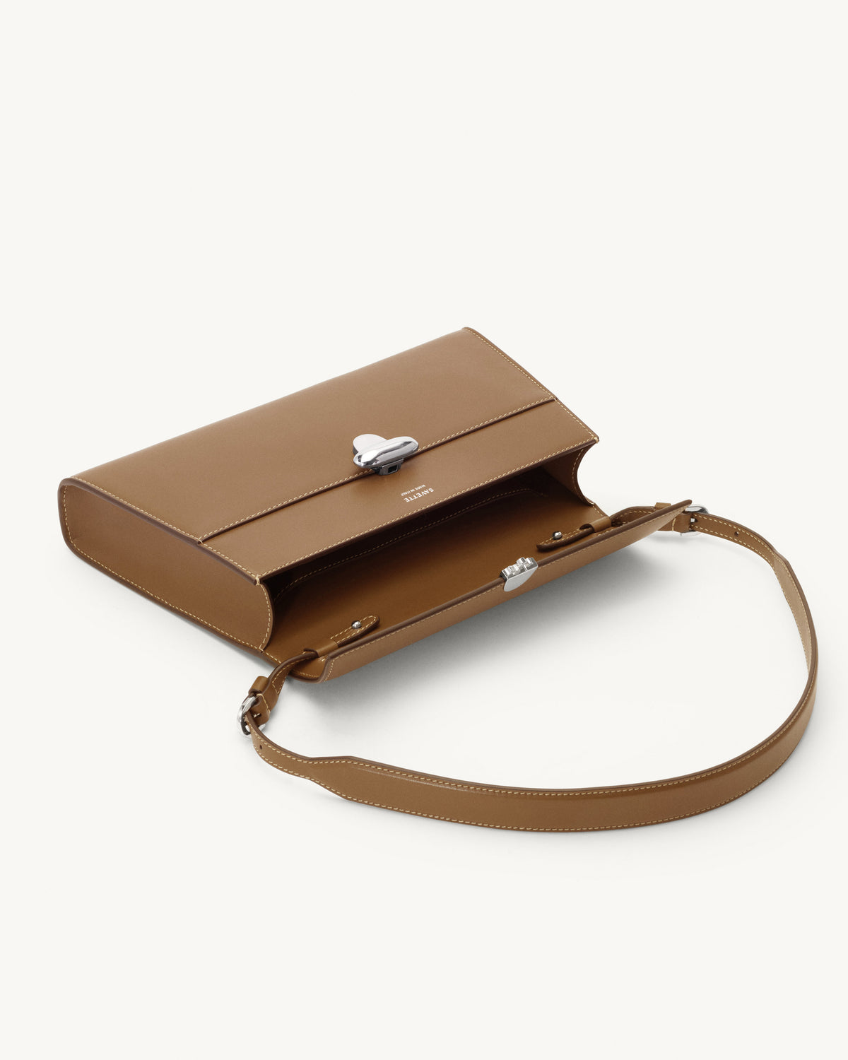 interior view of a saddle brown leather bag with a silver clasp on a white background
